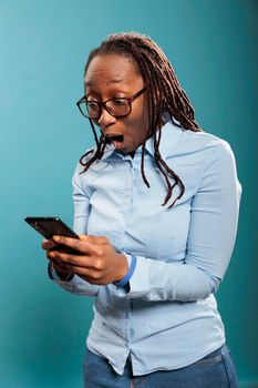 Shocked african american woman with touchscreen smartphone device astonished by received messages.