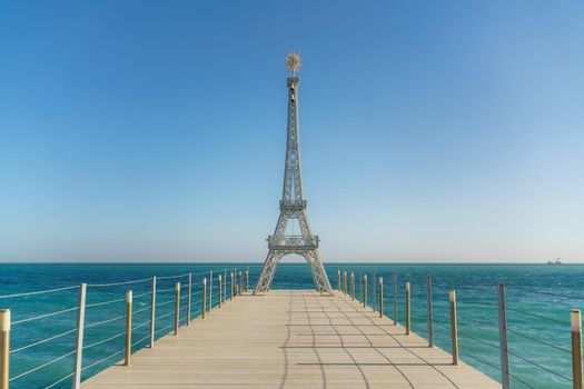 Large model of the Eiffel Tower on the beach.