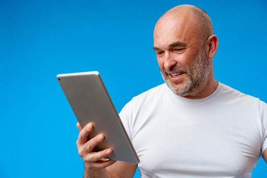Handsome middle age man with digital tablet against blue background