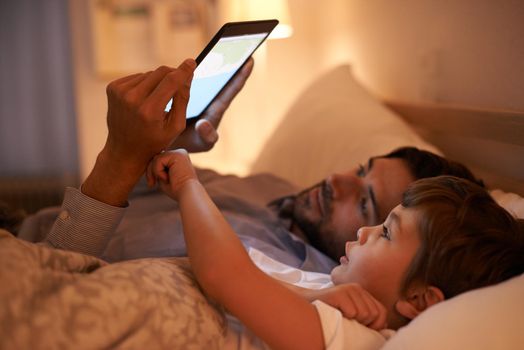 Modern bedtime story. A father reading a bedtime story to his son from an e-reader.