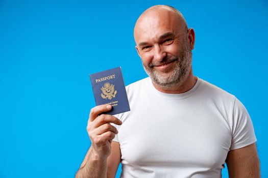 Middle age man holding passport with a happy face against blue background