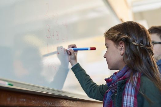 Shes got a bright young mind. Shot of an elementary school girl writing on a whiteboard in class.
