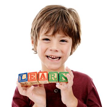 Play is the highest form of learning. Studio shot of a cute little boy holding building blocks that spell the world learn against a white background.