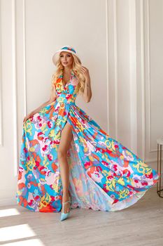 A beautiful sweet blonde woman in a bright outfit, a long skirt with a flower print, wavy hair,studio.
