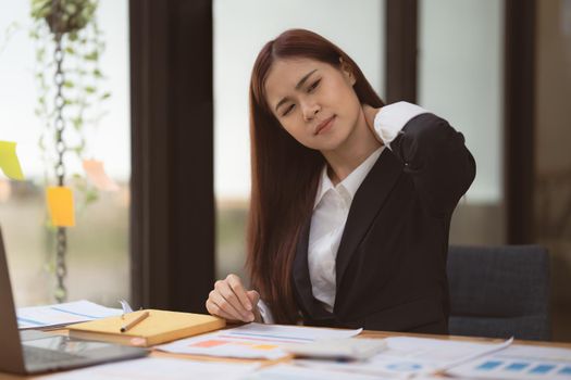 Image of Asian Business Woman relieve pain her neck suffering from sedentary work. office syndrome concept.