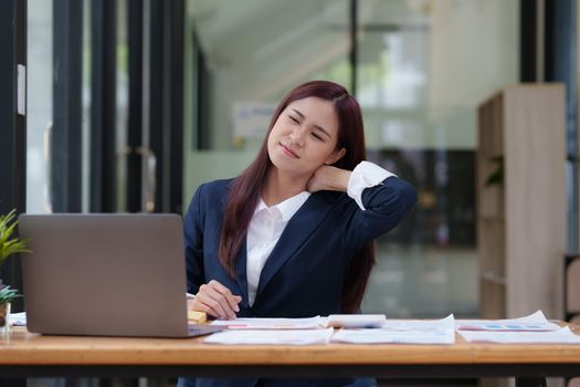 Image of Asian Business Woman relieve pain her neck suffering from sedentary work. office syndrome concept.
