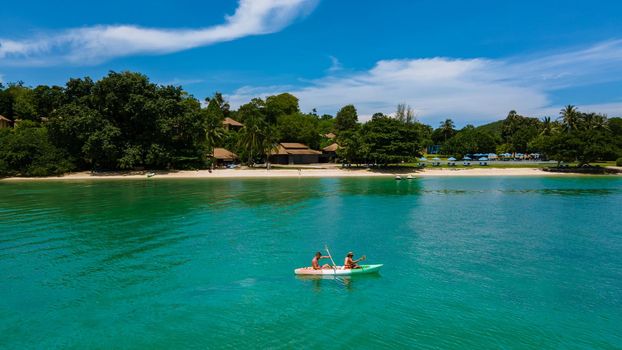 couple in kayak in the ocean of Phuket Naka Island Thailand, men and woman in kayak at a tropical island with palm trees and mangrove forrest
