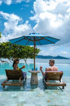 couple European man and Asian woman in infinity pool in Thailand looking out over the ocean, luxury vacation in Thailand