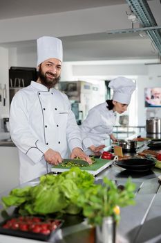 Smiling head chef cooking gastronomic food while getting garnish ready in restaurant professional kitchen.