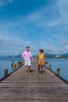 couple men and woman on a tropical isalnd with wooden pier jetty,