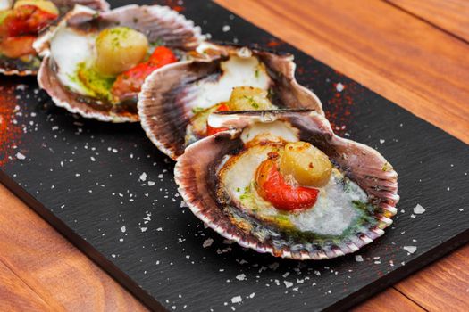 Cooked scallops on blackstone slate plate with species. Variety of Mediterranean seafood.