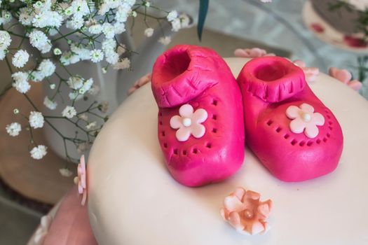 Baby shower cake with little pink marzipan booties for a girl and a floral arrangement
