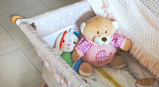 Baby cot or crib with cute soft cuddly toys and white blanket