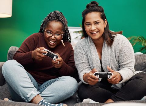 Shot of two young women playing video games on the sofa at home.