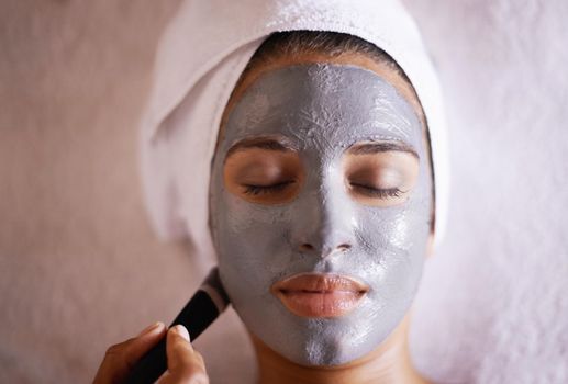 Pampering her skin with a facial treatment. Shot of a young woman enjoying a facial treatment at a spa.