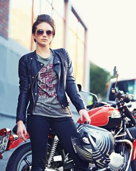 Riding with an attitude. Shot of a young and stylish female motorcycle rider outside.
