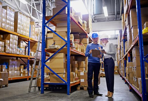 We know where every order is in this warehouse. Shot of a man and woman inspecting inventory in a large distribution warehouse.