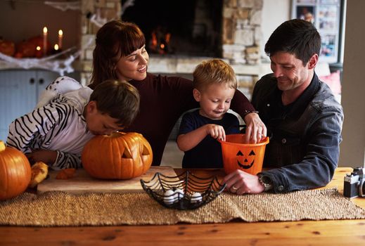 Were digging into the halloween festivities. Shot of an adorable young family carving out pumpkins and celebrating halloween together at home.