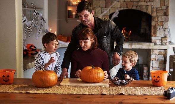 Time to carve out the good times. Shot of an adorable young family carving out pumpkins and celebrating halloween together at home.