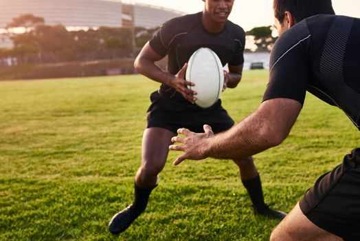 Is he going to tackle me. Cropped shot of two handsome sportsmen playing rugby during a training session during the day.