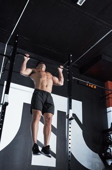 Do the work, reap the benefits. Shot of a young man lifting doing pull ups at a gym.