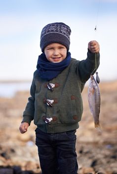 Look, its my biggest catch yet. Portrait of a cute little boy holding the fish he caught.