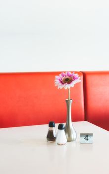 Indoor table setting in a cafe copy-space with flower in pot, salt and pepper shakers and metal number marker