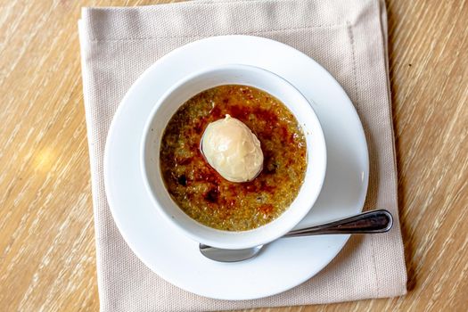 Delicious creme brulee with scoop of ice cream, fresh berries and mint on light table