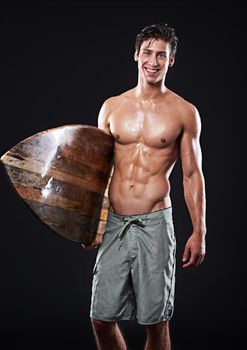 Wave rider with a great smile. Studio shot of a young surfer with a vintage board.
