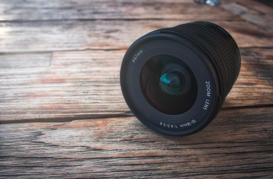 Camera lens on a rustic wooden table with soft light