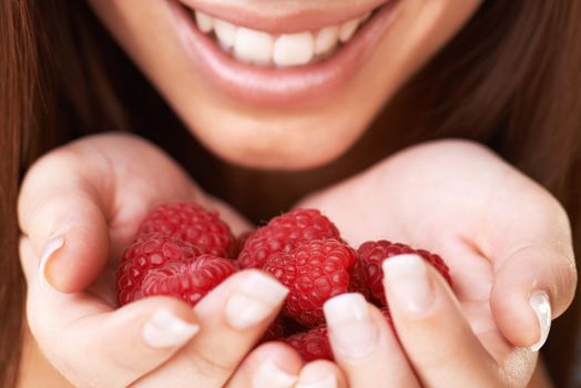 Raspberry delight. Cropped image of a happy young woman holding a bunch of raspberries.