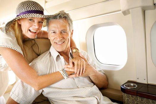 Excited to be headed on holiday. Smiling senior couple on an airplane heading overseas - portrait.
