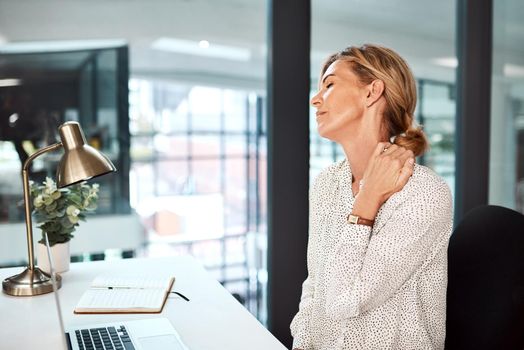 Its too uncomfortable to work like this. Shot of a mature businesswoman experiencing neck pain while working in an office.