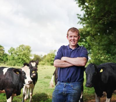 The agribusiness is booming. Portrait of a male farmer standing with his arms folded on his dairy farm.