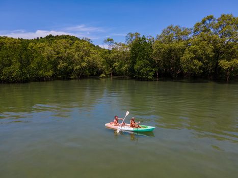 couple in kayak in the ocean of Phuket Naka Island Thailand, men and woman in kayak at a tropical island with palm trees and mangrove forrest