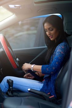 It takes a second to save a life. Shot of an attractive young woman buckling up before driving her car.