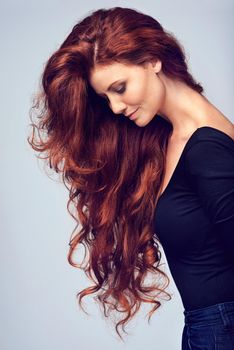Go on, let your hair down. Studio shot of a young woman with beautiful red hair posing against a gray background.