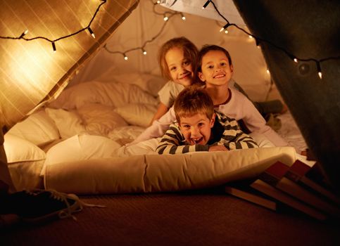 Blanket fort fun. Shot of three young children in a blanket fort.