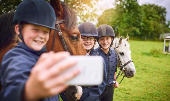 Horsing around on the ranch. Shot of a group of young friends taking a selfie while going horseback riding.