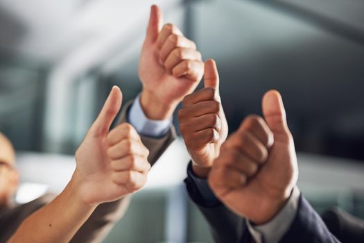 Thumbs up all round. Closeup shot of a group of businesspeople giving thumbs up together.
