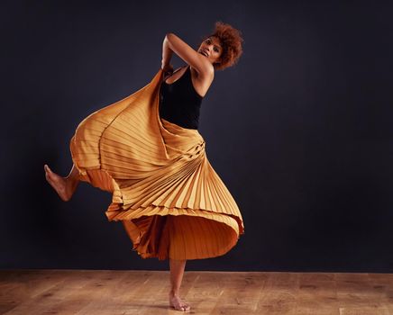 Earth dance. Female contemporary dancer in a dramatic pose against dark background.