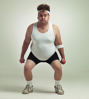 Deep squat. Portrait of an overweight man squatting and lifting dumbbells.