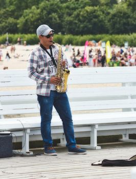 Sopot / Poland - August 3 2019: A saxophonist busker blowing the sax for money on the pier