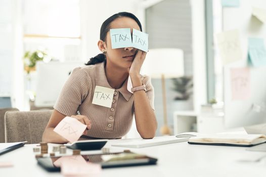 Tax is such a deathly dull topic. Shot of a young businesswoman covered in sticky notes while working on her taxes in an office.