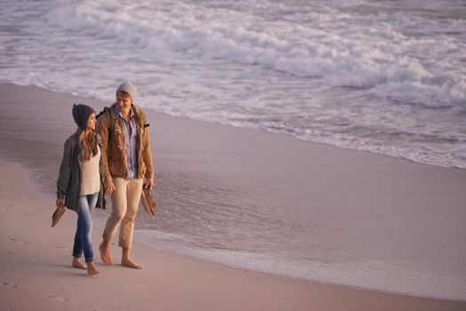Forever is not enough with you. Shot of a young couple enjoying a romantic stroll on the beach.