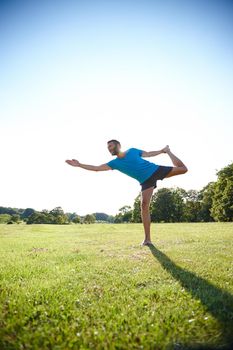 Challenge yourself. Full length shot of a handsome mature man doing yoga outdoors.