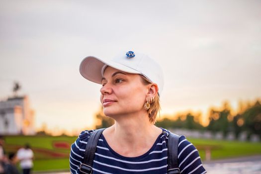 Portrait of a girl in a cap on the background of an open-air urban landscape. Travel. Lifestyle in the city. Center, streets. Summer, a walk.