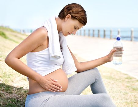 Healthy mom = healthy baby. A pregnant woman resting from her workout outdoors.