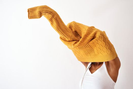 Its knitwear season. Studio shot of an unrecognizable woman getting dressed against a white background.