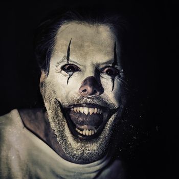 Halloween brings out the crazy in you. Portrait of an evil clown with face paint on a black background.